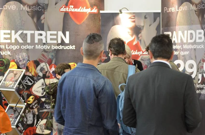 Bandshop GmbH – Messestand auf der Musikmesse Frankfurt: Messestand mit Besuchern vor der Plektren-Wand